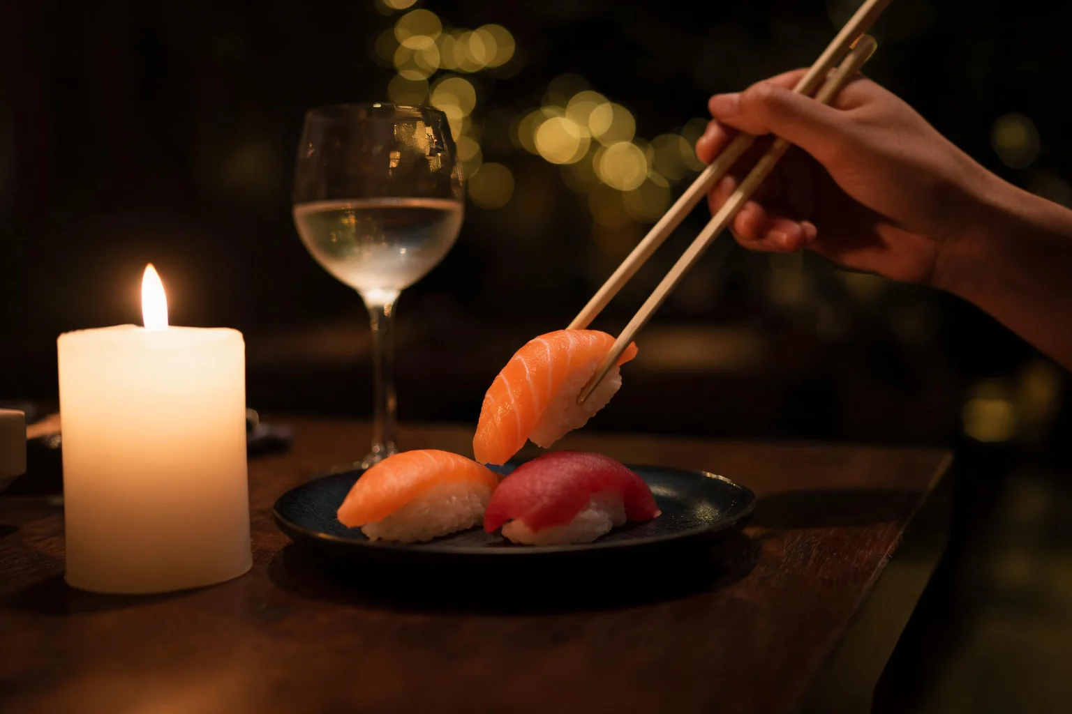 A table set for the evening, a lit candle, chopsticks and sushi, close up